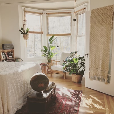 棕色木框白色软垫椅子，位于卧室内绿色室内叶子植物之间